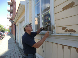 Stefan Källberg skrapar färg på Gula Huset